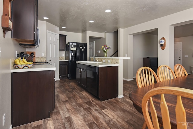 kitchen featuring sink, dark brown cabinets, black appliances, an island with sink, and dark hardwood / wood-style flooring