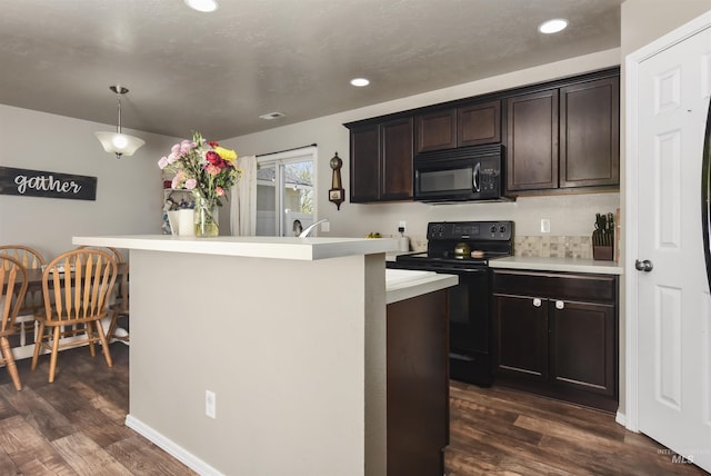 kitchen featuring a kitchen island with sink, pendant lighting, black appliances, and dark brown cabinetry