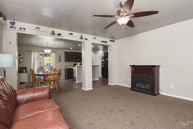 living room featuring dark colored carpet, ceiling fan, and a textured ceiling