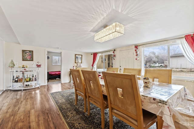 dining space with wood-type flooring and an inviting chandelier