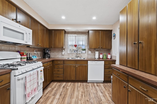 kitchen featuring decorative backsplash, light hardwood / wood-style floors, white appliances, and sink