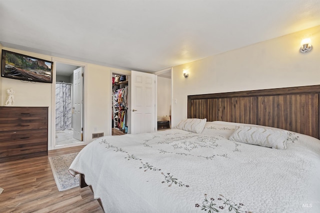 bedroom featuring a walk in closet, a closet, hardwood / wood-style floors, and ensuite bathroom