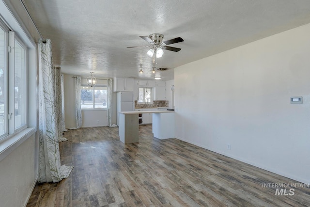 kitchen with white cabinetry, white refrigerator, light hardwood / wood-style floors, and backsplash