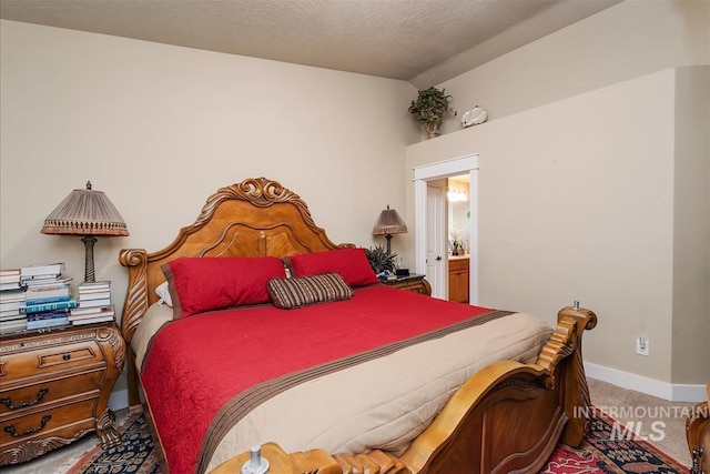 bedroom with vaulted ceiling, a textured ceiling, ensuite bathroom, baseboards, and carpet flooring