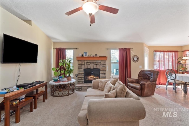 carpeted living room with a ceiling fan, a textured ceiling, and a fireplace