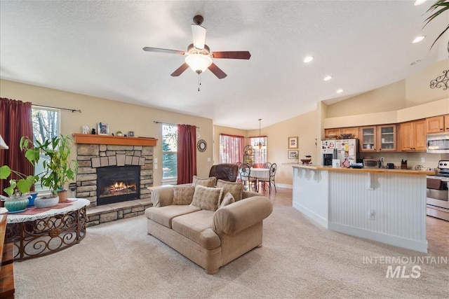 living area with baseboards, light colored carpet, lofted ceiling, ceiling fan, and a fireplace