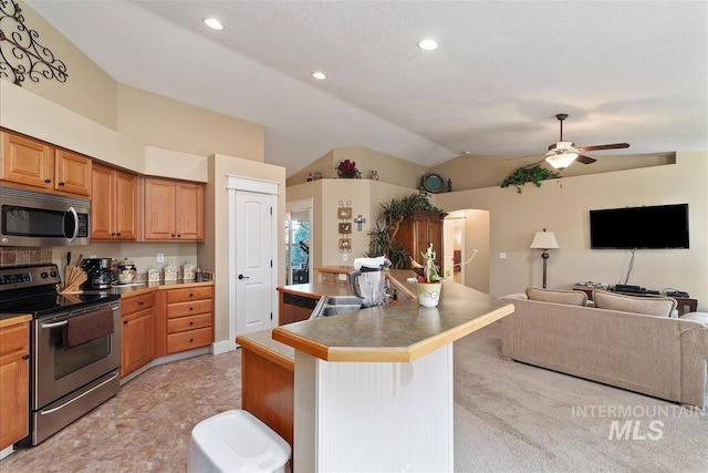 kitchen featuring lofted ceiling, stainless steel appliances, a breakfast bar area, open floor plan, and ceiling fan