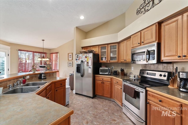 kitchen with brown cabinets, lofted ceiling, stainless steel appliances, a sink, and glass insert cabinets