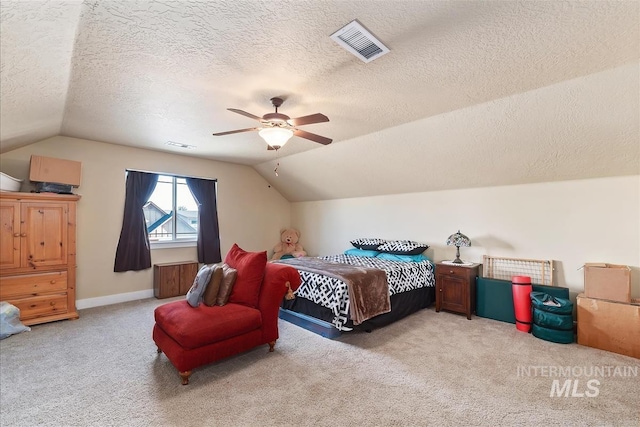 carpeted bedroom featuring a textured ceiling, vaulted ceiling, and visible vents