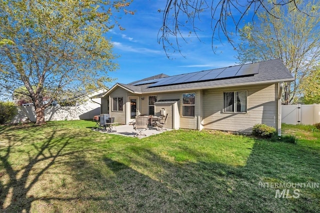 rear view of house featuring a gate, a lawn, a fenced backyard, a patio, and solar panels