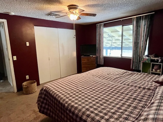 carpeted bedroom featuring ceiling fan, a closet, and a textured ceiling