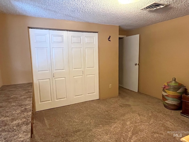 unfurnished bedroom featuring carpet flooring, a closet, and a textured ceiling