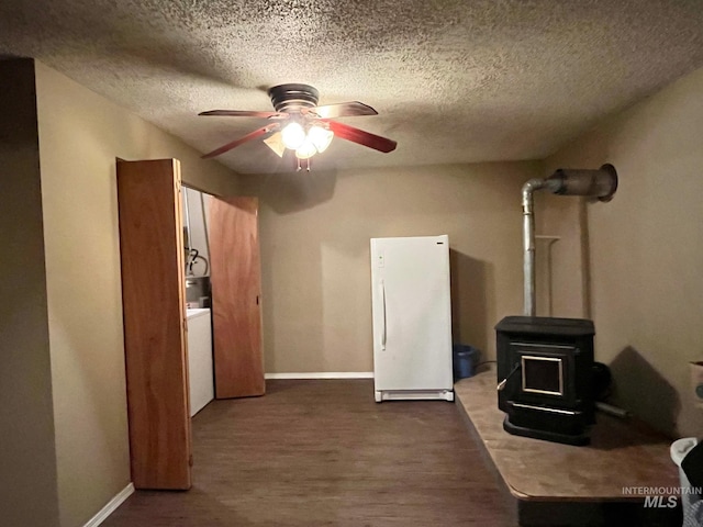 interior space with a textured ceiling, a wood stove, dark hardwood / wood-style floors, ceiling fan, and washer / clothes dryer