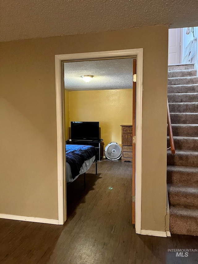 corridor with dark hardwood / wood-style flooring and a textured ceiling