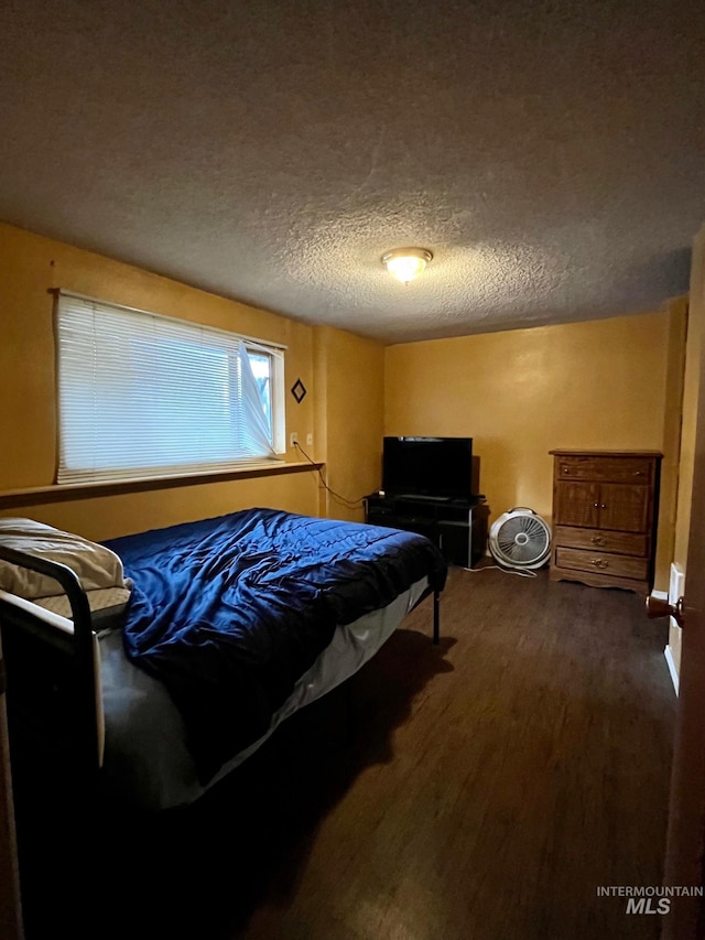 bedroom with dark hardwood / wood-style floors and a textured ceiling