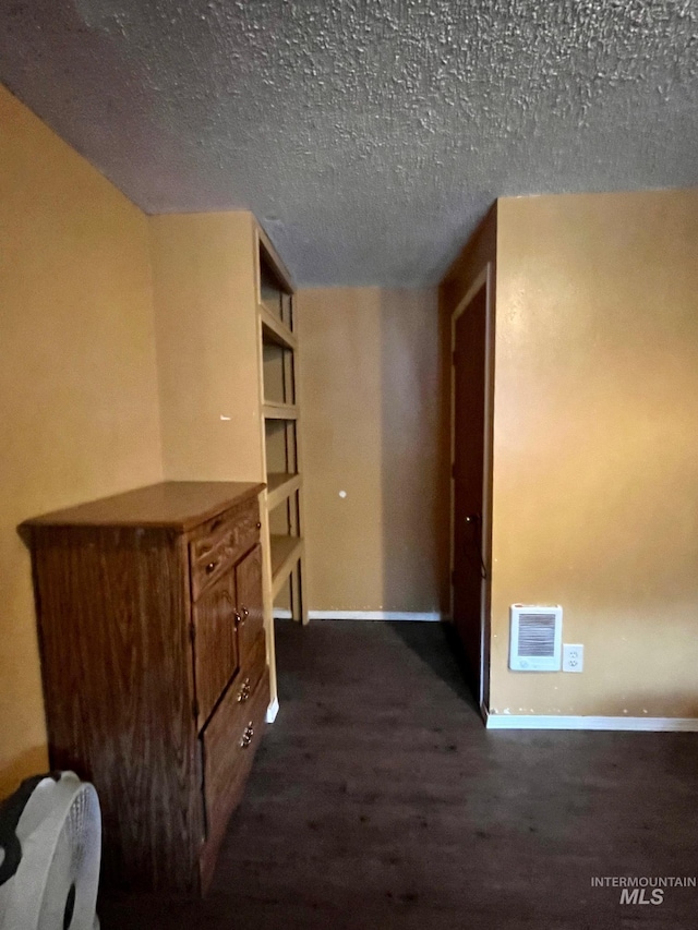 corridor with dark hardwood / wood-style floors and a textured ceiling