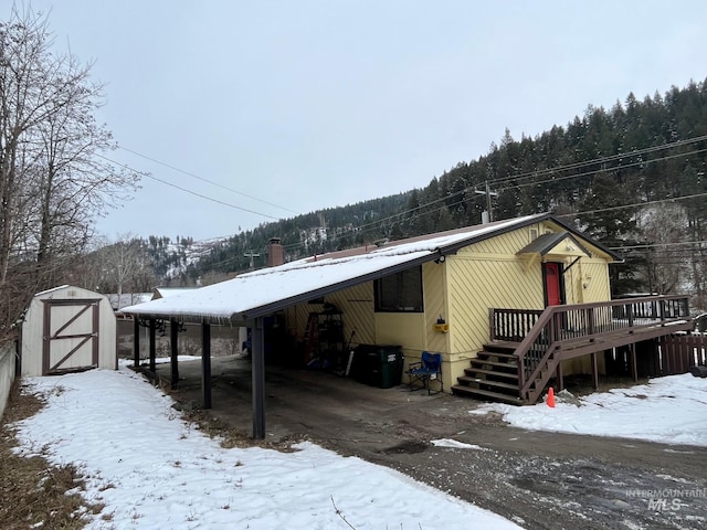 view of front of property with a carport, a deck, and a storage shed