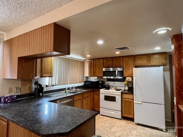 kitchen with stainless steel appliances, kitchen peninsula, sink, and a textured ceiling