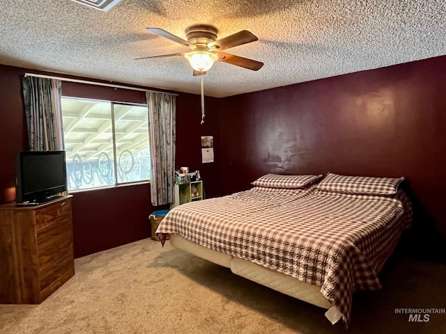 carpeted bedroom with ceiling fan and a textured ceiling