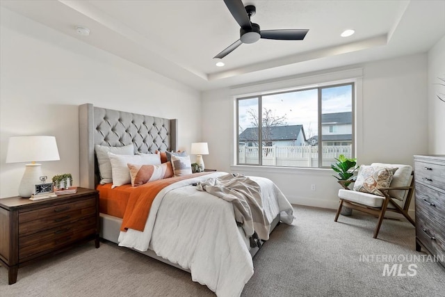 bedroom featuring recessed lighting, a tray ceiling, light carpet, and baseboards