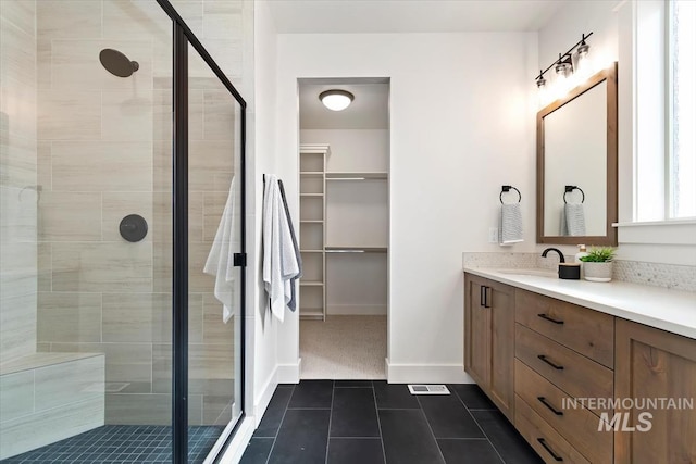 full bath featuring a spacious closet, tile patterned flooring, baseboards, a stall shower, and vanity