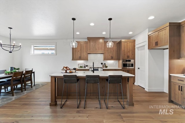 kitchen with light countertops, tasteful backsplash, light wood finished floors, and oven