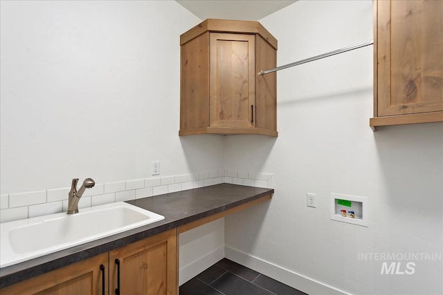 laundry room with baseboards, dark tile patterned floors, washer hookup, cabinet space, and a sink