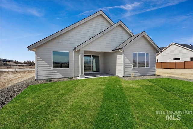 rear view of property featuring a lawn and fence