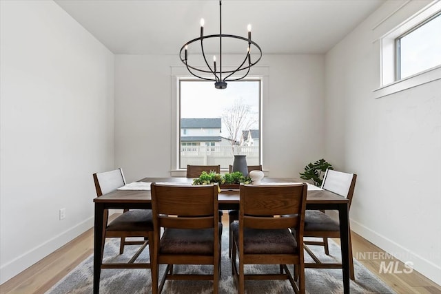 dining area with baseboards, light wood-style floors, and an inviting chandelier