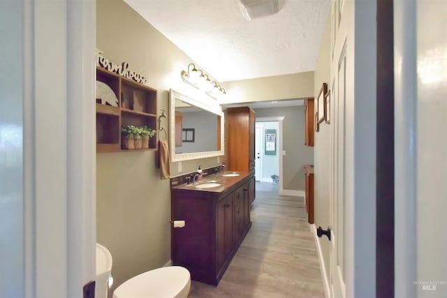 bathroom featuring hardwood / wood-style flooring, vanity, a textured ceiling, and toilet
