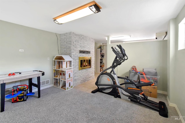 exercise area featuring a brick fireplace and light carpet
