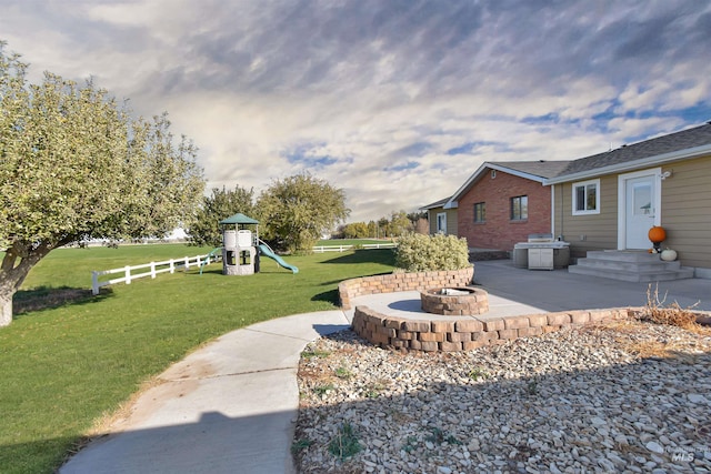 view of yard featuring a patio area, a playground, and an outdoor fire pit