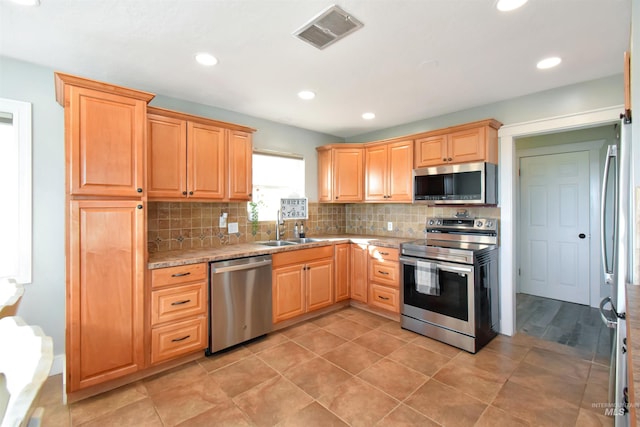 kitchen featuring light stone counters, sink, decorative backsplash, and stainless steel appliances