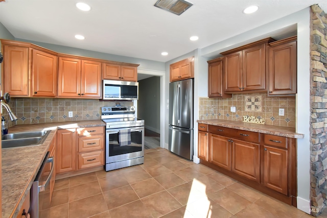 kitchen featuring appliances with stainless steel finishes, sink, light tile patterned floors, and backsplash