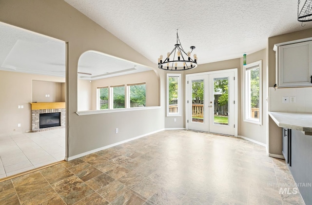 511 Bitterbrush Ave, Nampa, ID 83686 - unfurnished dining area featuring a chandelier, a fireplace, french doors, baseboards, and a textured ceiling
