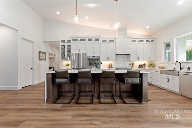 1889 W Winter Camp Ct, Boise, ID 83703 - kitchen with stainless steel appliances, lofted ceiling, a center island, backsplash, and white cabinets