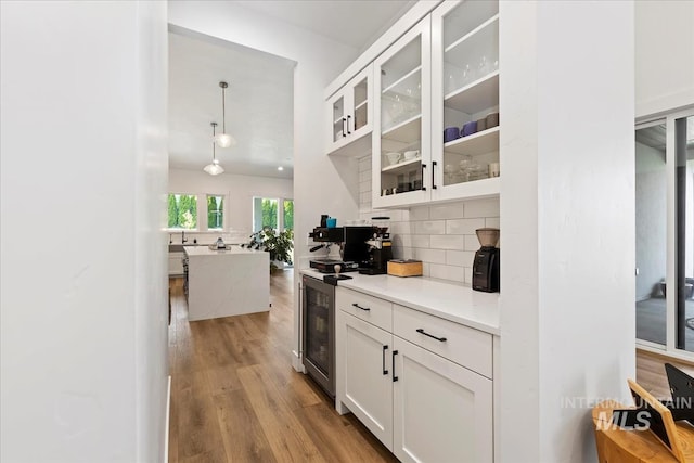 1889 W Winter Camp Ct, Boise, ID 83703 - kitchen featuring wine cooler, wood finished floors, tasteful backsplash, and white cabinetry