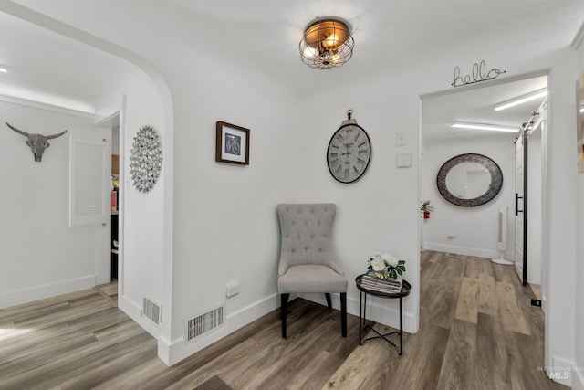 sitting room featuring arched walkways, visible vents, baseboards, and wood finished floors