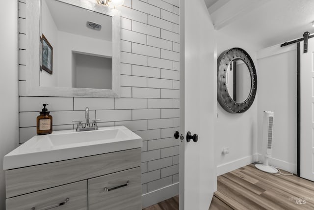 bathroom with visible vents, tile walls, vanity, and wood finished floors
