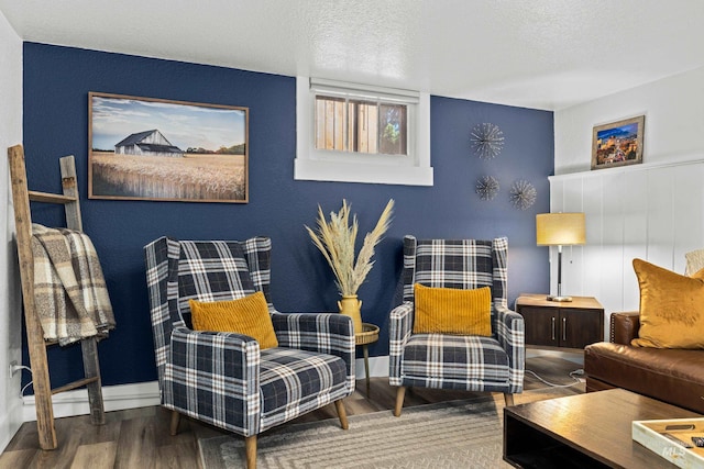 living area with a textured ceiling, baseboards, and wood finished floors
