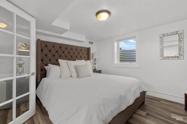 bedroom with visible vents, baseboards, and wood finished floors