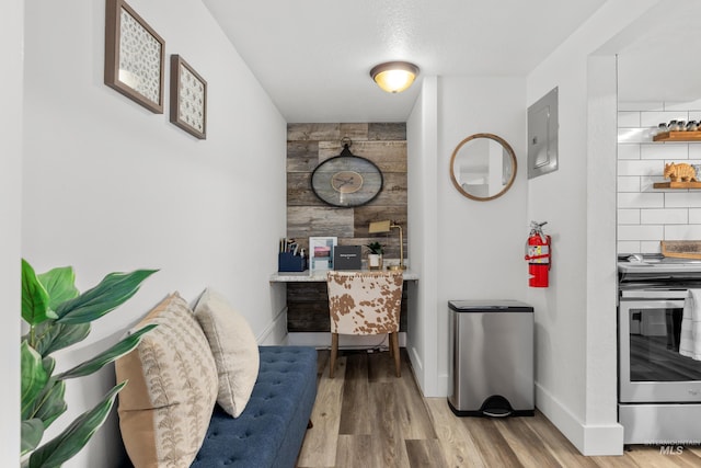 interior space with electric panel, baseboards, and wood finished floors