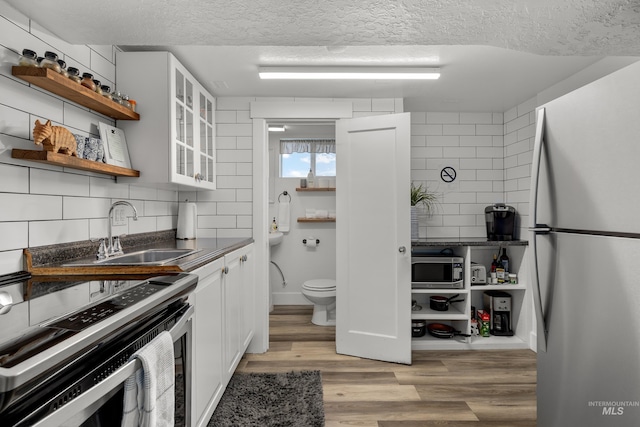 kitchen featuring a textured ceiling, dark countertops, open shelves, and stainless steel appliances