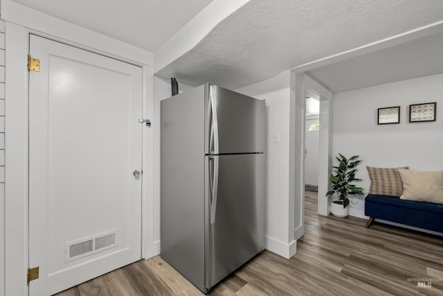 kitchen featuring visible vents, baseboards, freestanding refrigerator, and wood finished floors