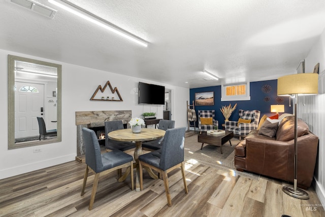 dining area with visible vents, a textured ceiling, baseboards, and wood finished floors