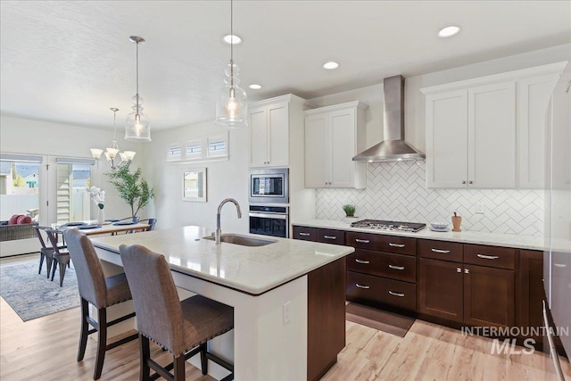 12740 S Alzano Way, Nampa, ID 83686 - kitchen with wall chimney range hood, stainless steel appliances, a sink, a breakfast bar area, and decorative backsplash