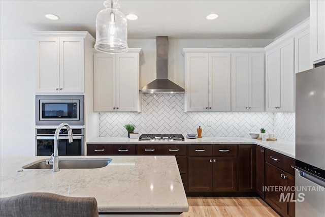 12740 S Alzano Way, Nampa, ID 83686 - kitchen with wall chimney exhaust hood, stainless steel appliances, white cabinetry, dark brown cabinetry, and recessed lighting