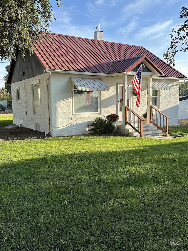 exterior space featuring a standing seam roof, a chimney, a lawn, and stucco siding