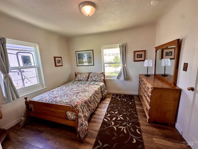 bedroom with a textured ceiling, baseboards, and wood finished floors