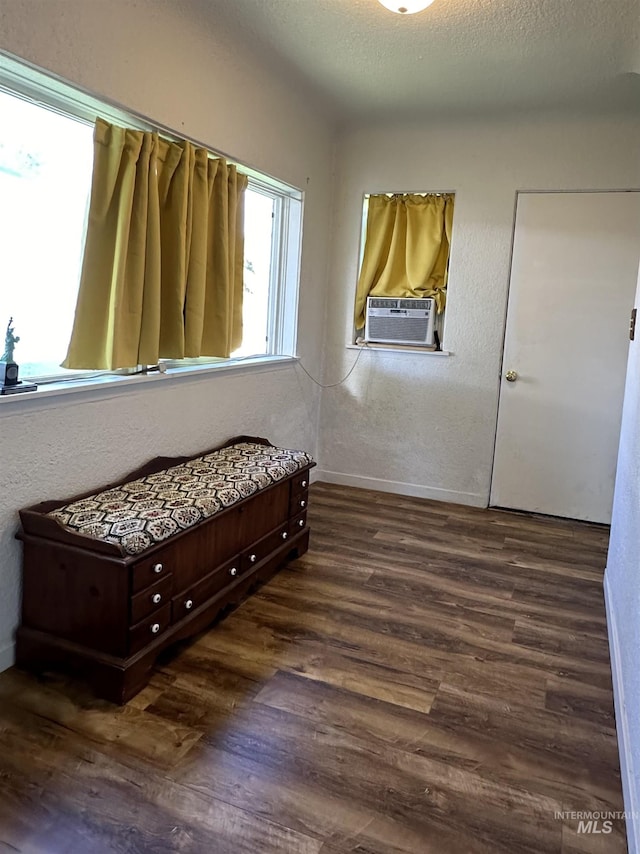 bedroom featuring a textured ceiling, cooling unit, wood finished floors, and a textured wall